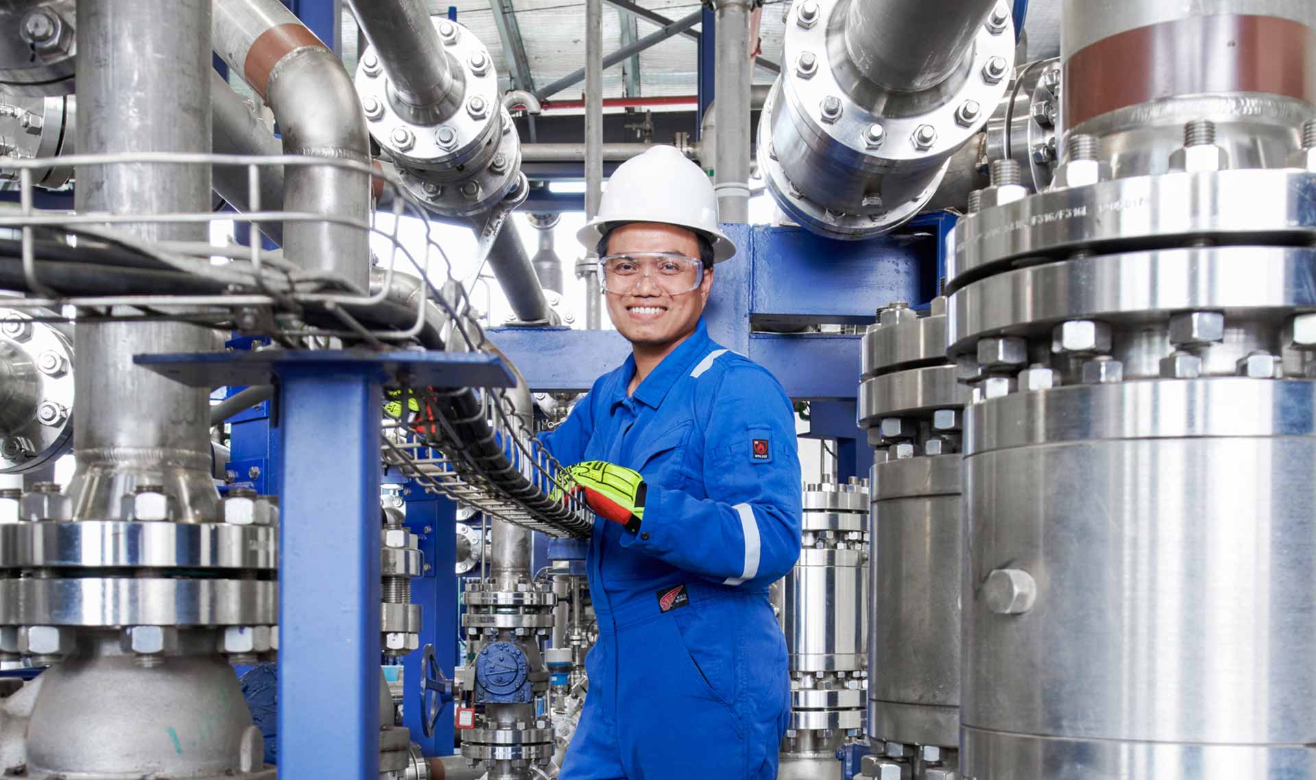 Engineer smiling among valves and machinery
